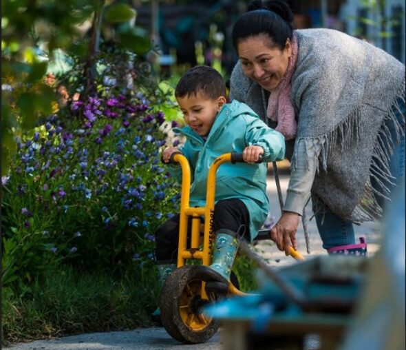 Child riding tricycle with adult assistance
