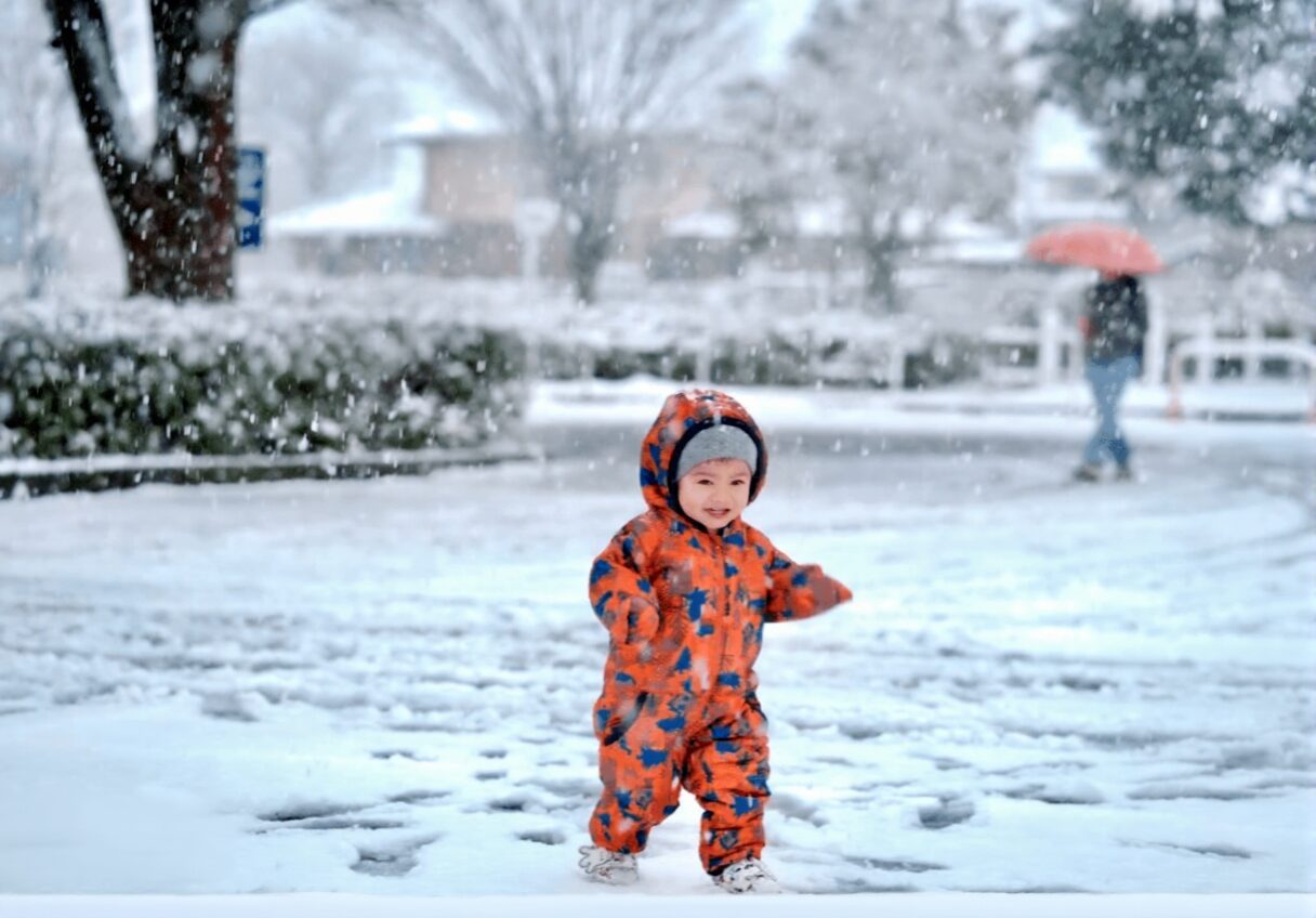 Toddler playing outside during snowfall