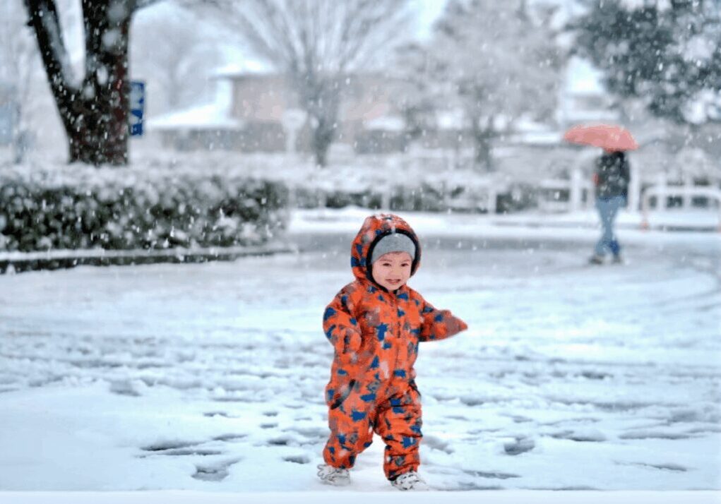 Toddler playing outside during snowfall